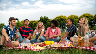 Gruppo di amici fa un pic nic sul prato. 