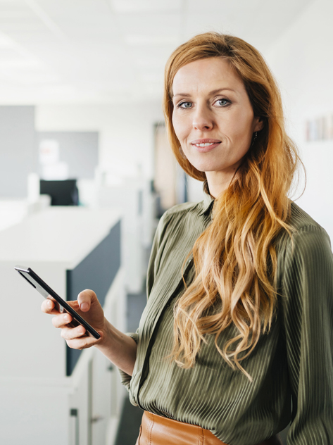 Donna sorridente con cellulare in mano in ufficio.