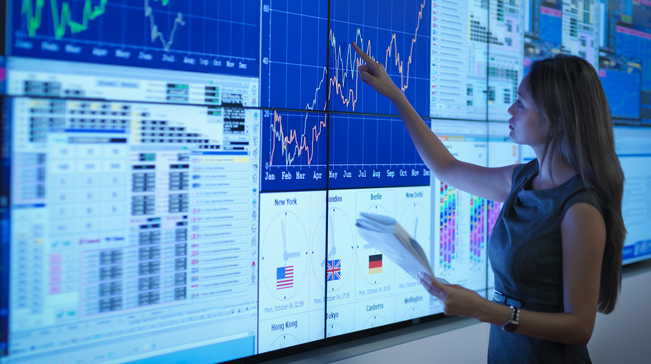 Analista finanziaria analizza grafici di andamento di mercato su schermo